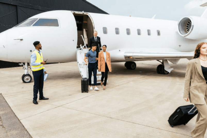 Travelers arriving beside a private jet while the crew coordinates on the ramp